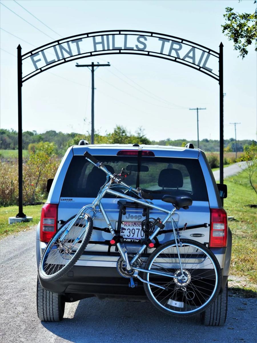 Flint Hills Trail sign. Car with bike rack underneath trail sign.