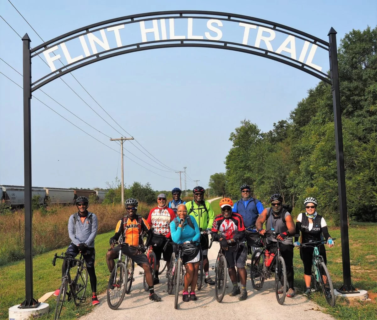 Members of the Major Taylor Cycling Club from Kansas City posing below the Flint Hills Trail sign